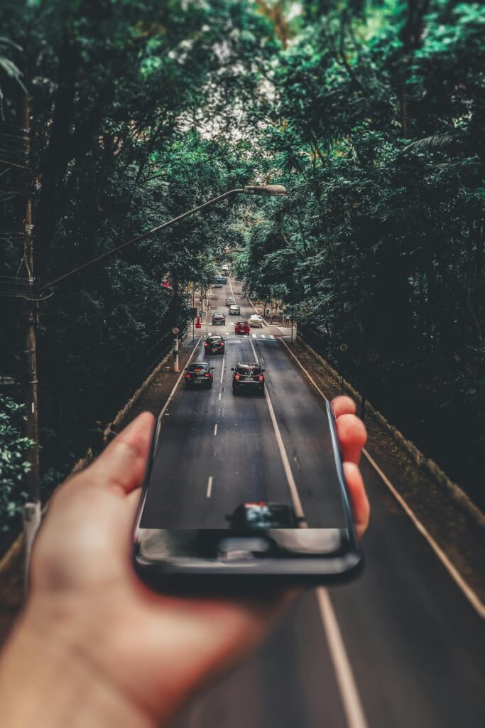 pexels-photo-799443-799443 Creative blend of technology and nature with smartphone framing a bustling road through forest.